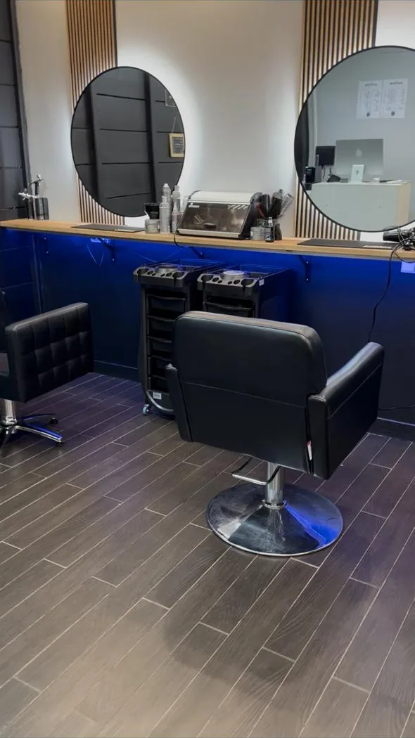 Poste de coiffage du salon avec miroir rond, plan de travail en bois et façade bleue
