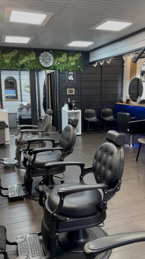 Alignement des fauteuils de barbier du Legend'Hair sous le plafond noir et le mur végétal